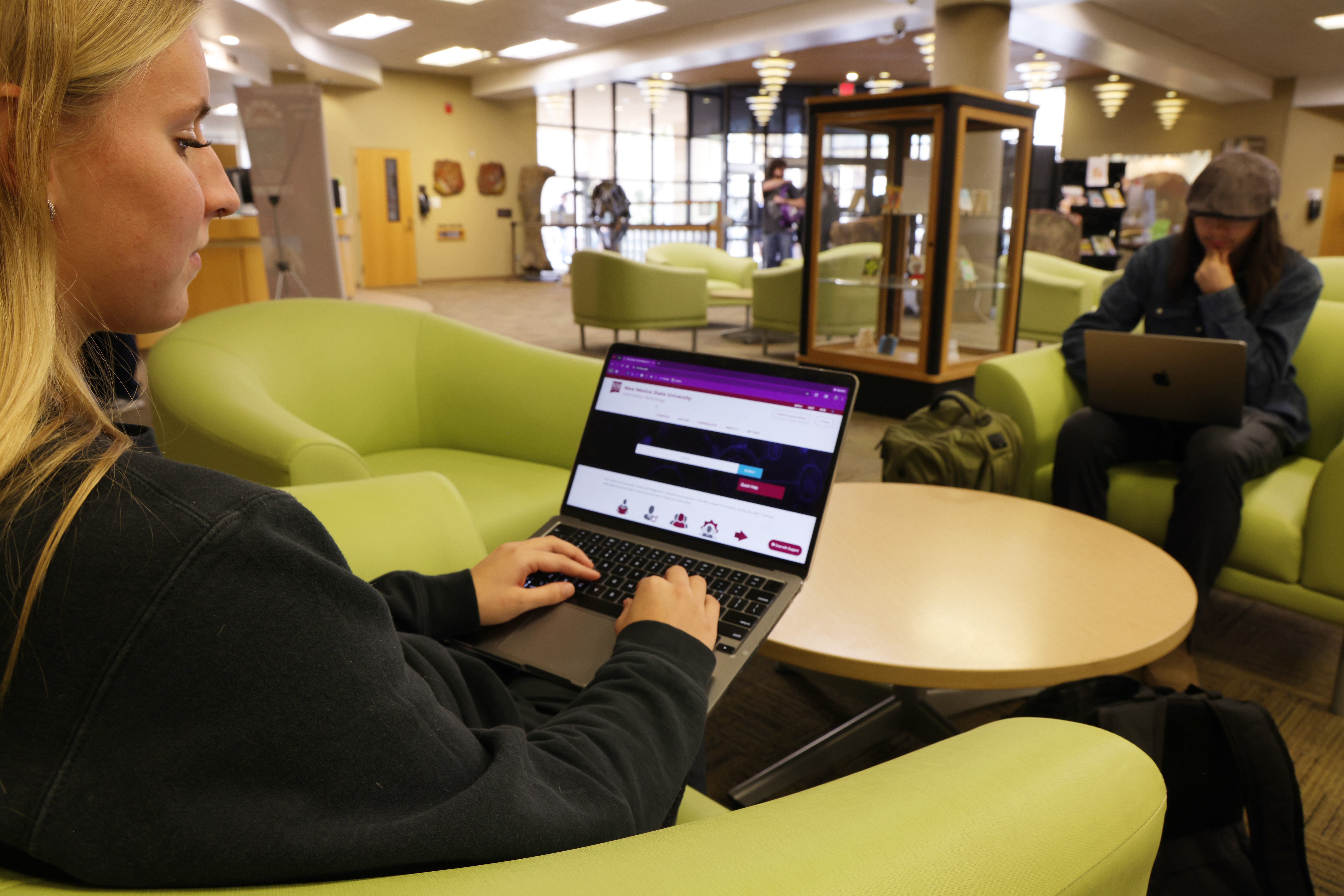 Student using a laptop in a library lounge.